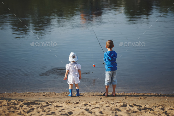 boy and girl with rod on coast of river Stock Photo by ababaka