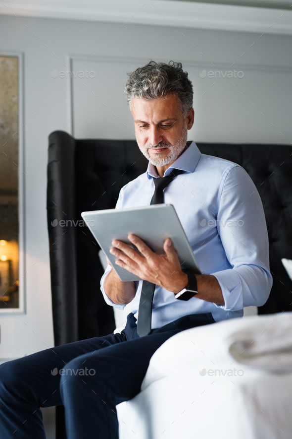 Mature businessman with tablet in a hotel room.