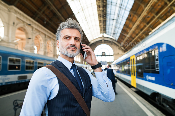 Mature businessman with smartphone on a train station.