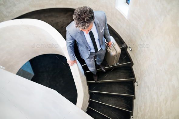 Businessman with suitcase walking down the stairs.