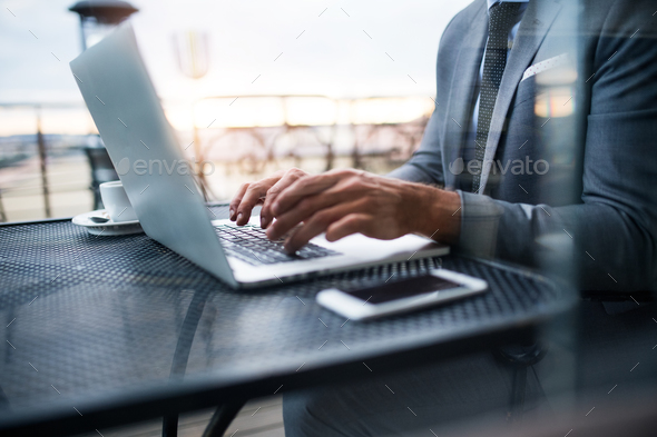 Mature businessman with laptop outside a cafe.