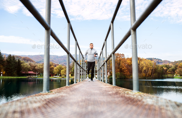 Young athlete with smartphone running in park in autumn. - Stock Photo - Images