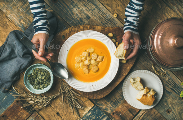 Fall warming pumpkin cream soup with seeds and bread - Stock Photo - Images