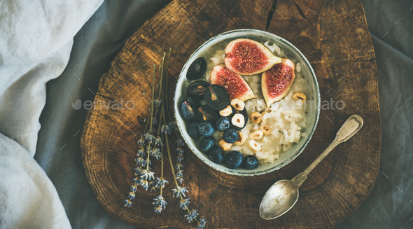 Rice coconut porridge with figs, berries and hazelnuts in bowl - Stock Photo - Images
