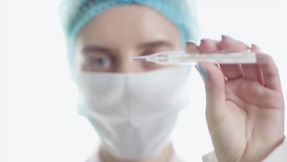 A Female Doctor in Medical Uniform is Looking at Camera and Showing Medical Mercury Thermometer alt
