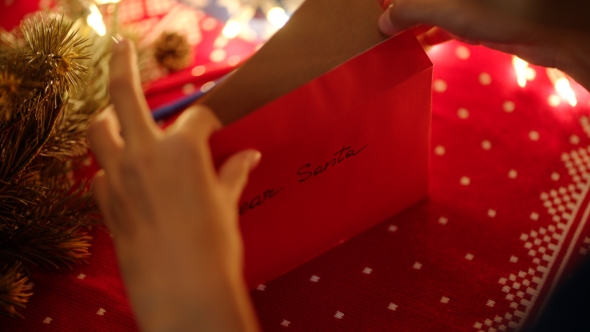 Putting a Christmas Letter in the Envelope To Santa  alt