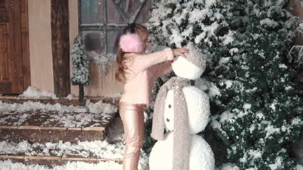  Child Adjusts Hat and Scarf on the Snowman