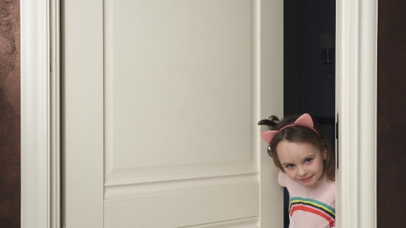 Little Girl Peeks Out From Behind the Door