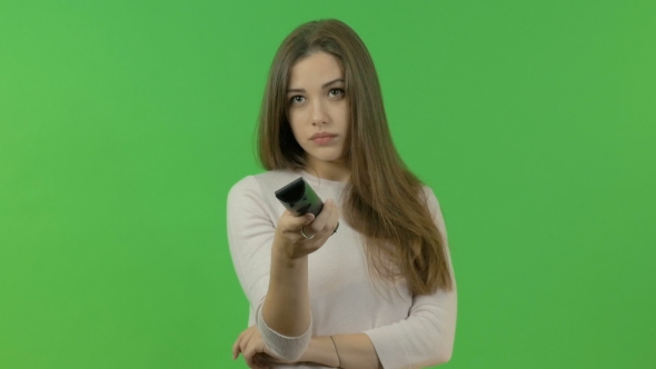 The White Girl Switches Channels on the TV Remote Control. On a Green Background.