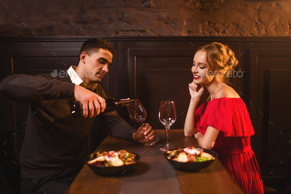 Man pours wine into a glass, couple in restaurant - Stock Photo - Images