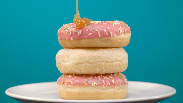 Three Rotating Delicious Pink Strawberry Flavor Donuts with Caramel Topping