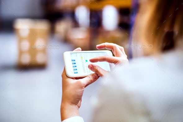 Woman warehouse worker with smartphone. - Stock Photo - Images
