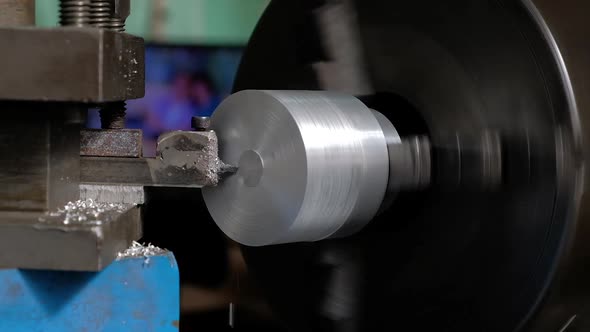 Worker handles aluminum metal piece on a lathe front view slow motion alt