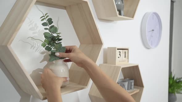 Woman Puts Decor and Flowers on the Shelves on the Wall