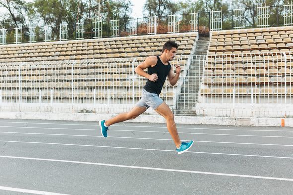Young athletic man running on the stadium in the morning - Stock Photo - Images