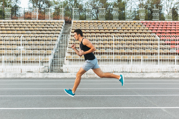 Young athletic man running on the stadium in the morning - Stock Photo - Images