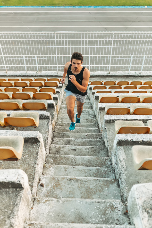 Image of young athletic man running by ladder at the stadium out - Stock Photo - Images