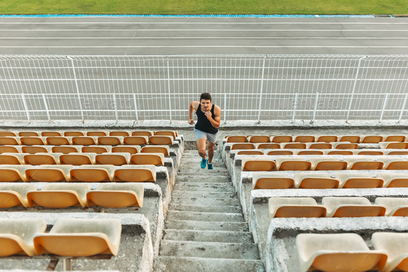 Image of young athletic man running by ladder at the stadium out - Stock Photo - Images