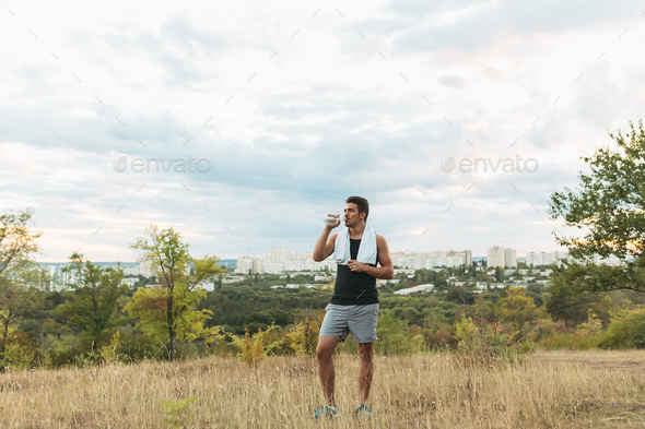 Healthy man drinking water on nature while resting - Stock Photo - Images