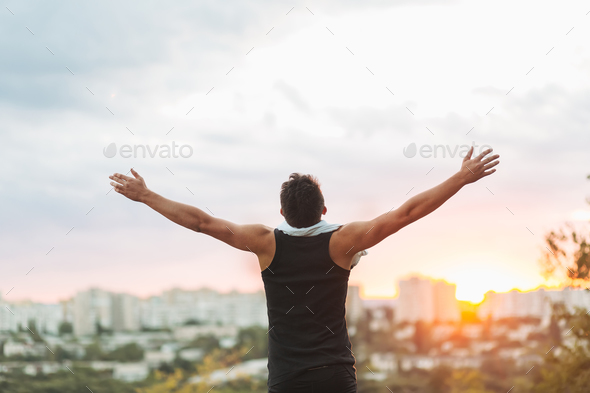 Young man raising hands over sunset sky after training - Stock Photo - Images