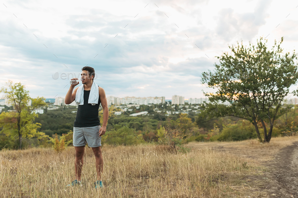Healthy man drinking water on nature while resting - Stock Photo - Images