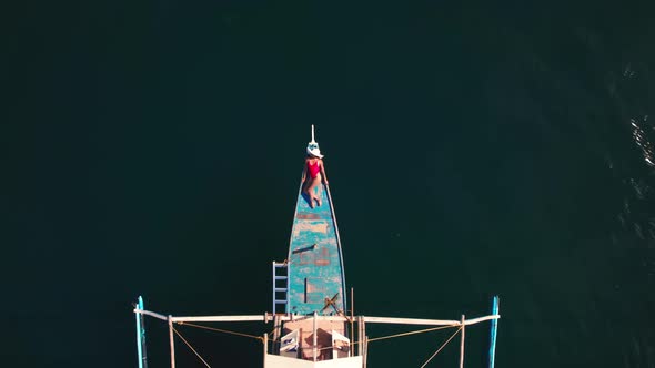 Drone Above Sea Towards Woman Sunbathing On Outrigger Boat alt