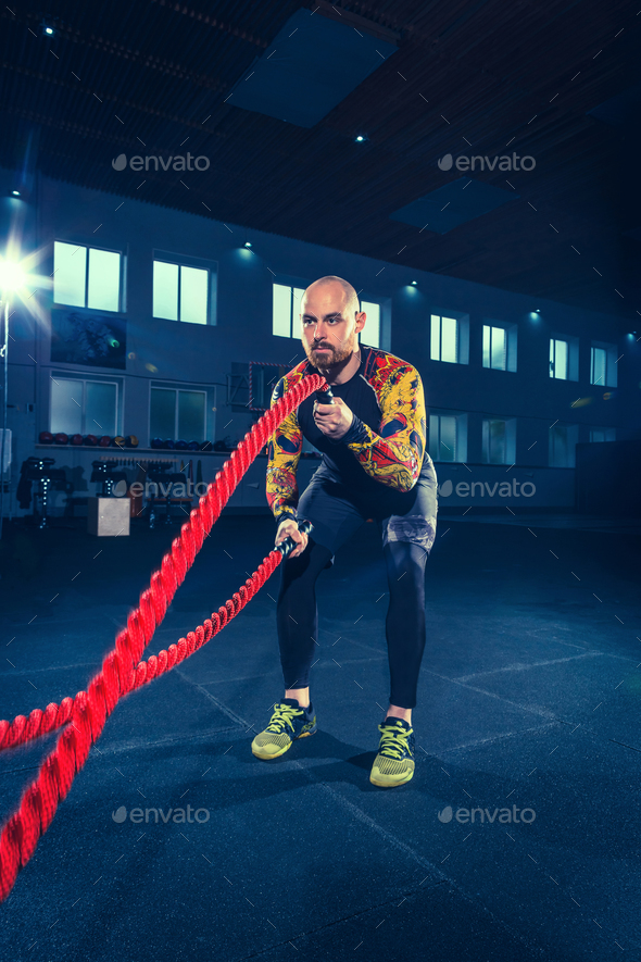 Men with battle rope battle ropes exercise in the fitness gym. CrossFit. - Stock Photo - Images