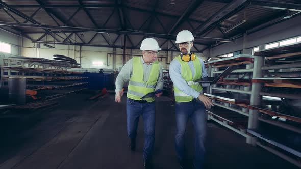 Male Inspectors Are Walking Along the Metal-factory Warehouse alt