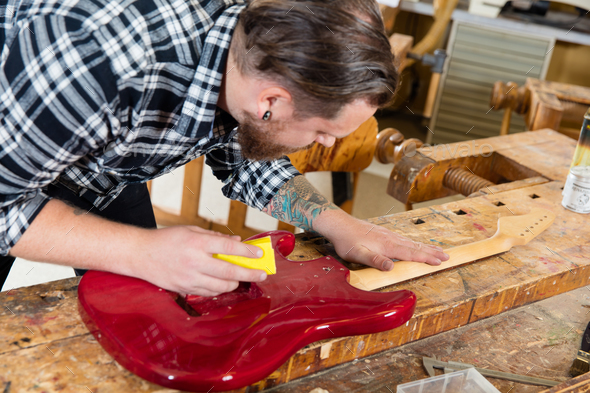 Close-up of craftsman sanding a guitar neck in wood at workshop - Stock Photo - Images