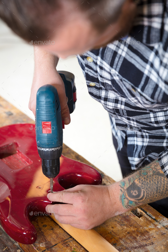 Environmental portrait of man working in workshop with guitar - Stock Photo - Images