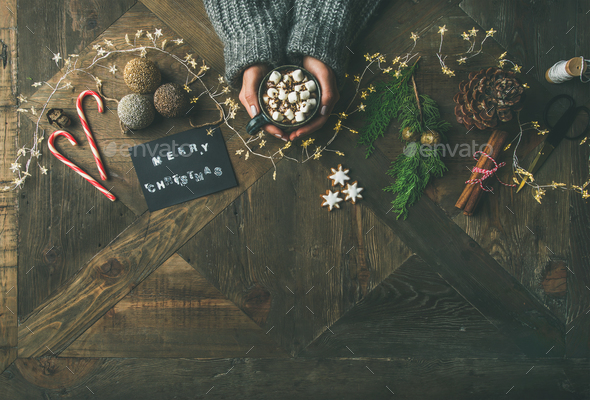 Flat-lay of greeting card, light garland, woman's hands holding mug - Stock Photo - Images