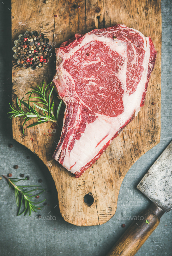 Raw beef steak rib-eye on board with seasoning, top view - Stock Photo - Images
