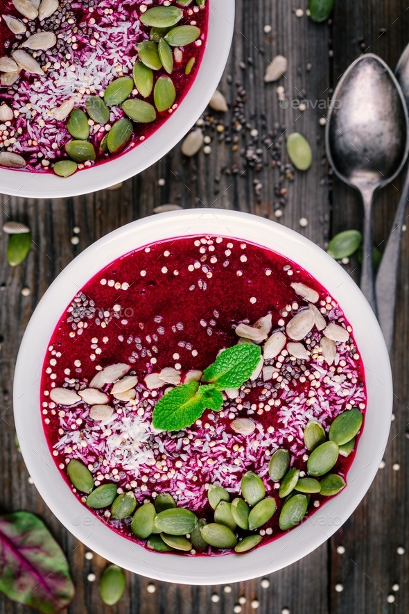 Beet smoothie bowl with chia seeds, coconut, pumpkin seeds, quinoa, sunflower seeds and mint - Stock Photo - Images