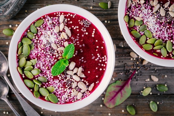 Beet smoothie bowl with chia seeds, coconut, pumpkin seeds, quinoa, sunflower seeds and mint - Stock Photo - Images