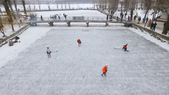 Aerial View of Men Playing Hockey on a Frozen Lake in a City Park in Winter