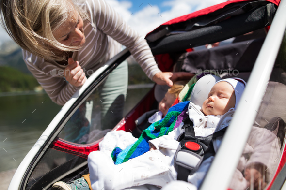 Senior woman and grandchildren in jogging stroller. Stock Photo by halfpoint