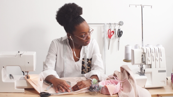 Happy Clothing Designer Is Working with Measurements on a Studio Table. alt