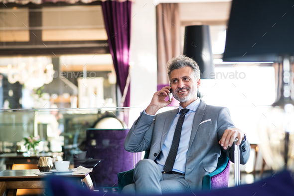Mature businessman with smartphone in a hotel lounge. - Stock Photo - Images