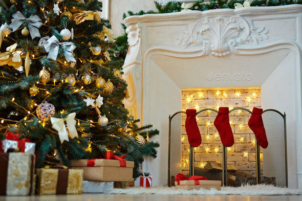 Decorated xmas tree, stack of gift-boxes and fireplace with red socks prepared for Christmas night Decorated xmas tree, stack of gift-boxes and fireplace with red socks prepared for Christmas night