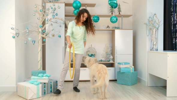 Girl with a Dog Is Playing with a Hoop in Room with Christmas Decorations