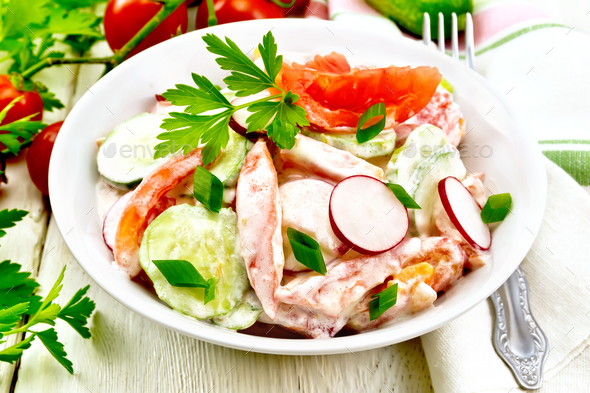 Salad from fresh vegetables and greens in plate on light board - Stock Photo - Images