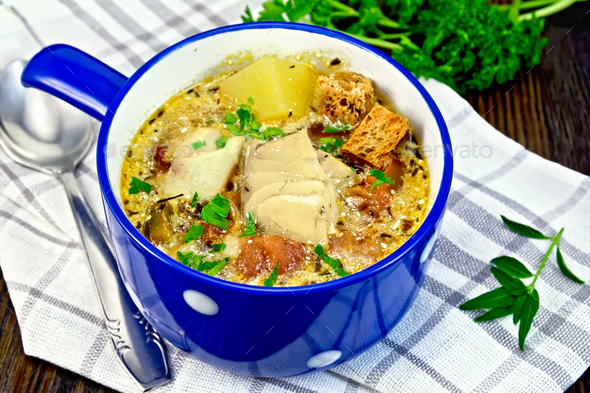Soup fish with vegetables and croutons on dark board - Stock Photo - Images