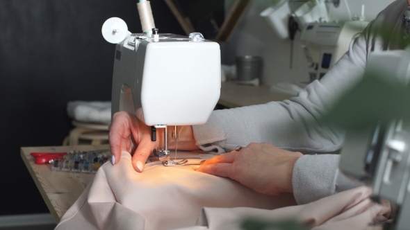 Senior Seamstress Is Working on a Sewing Machine at a Clothing Manufactory. alt