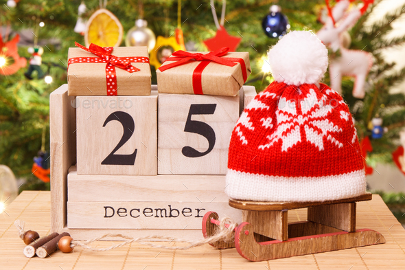 Date 25 December on calendar, gifts with sled and cap, christmas tree - Stock Photo - Images