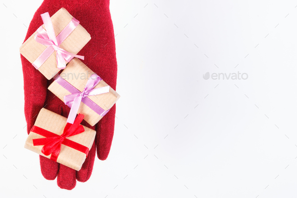 Hand of woman in gloves with gifts for Christmas or other celebration, copy space for text on white - Stock Photo - Images