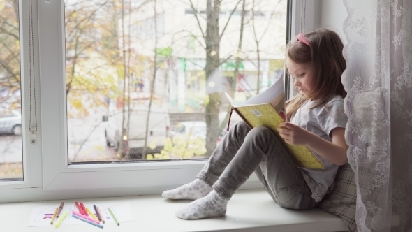 Little Girl Reading a Book on Window Sill