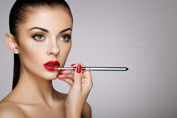 Beautiful woman paints lips with lipstick - Stock Photo - Images