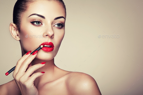 Beautiful woman paints lips with lipstick - Stock Photo - Images