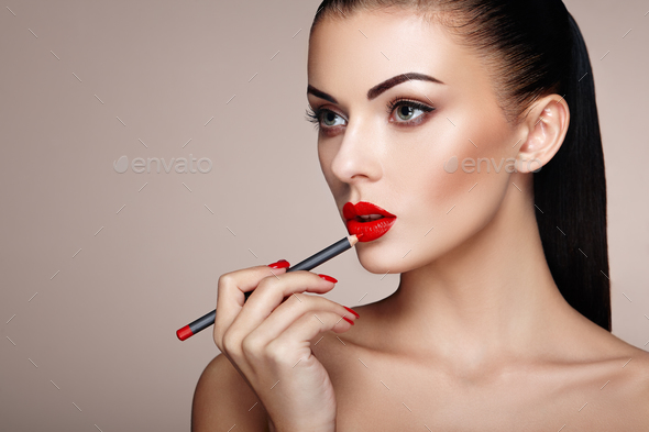 Beautiful woman paints lips with lipstick - Stock Photo - Images