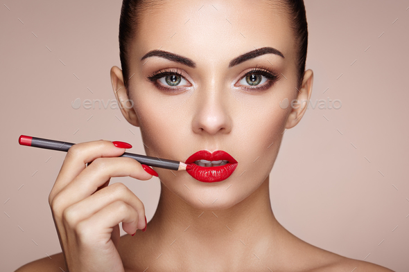Beautiful woman paints lips with lipstick - Stock Photo - Images
